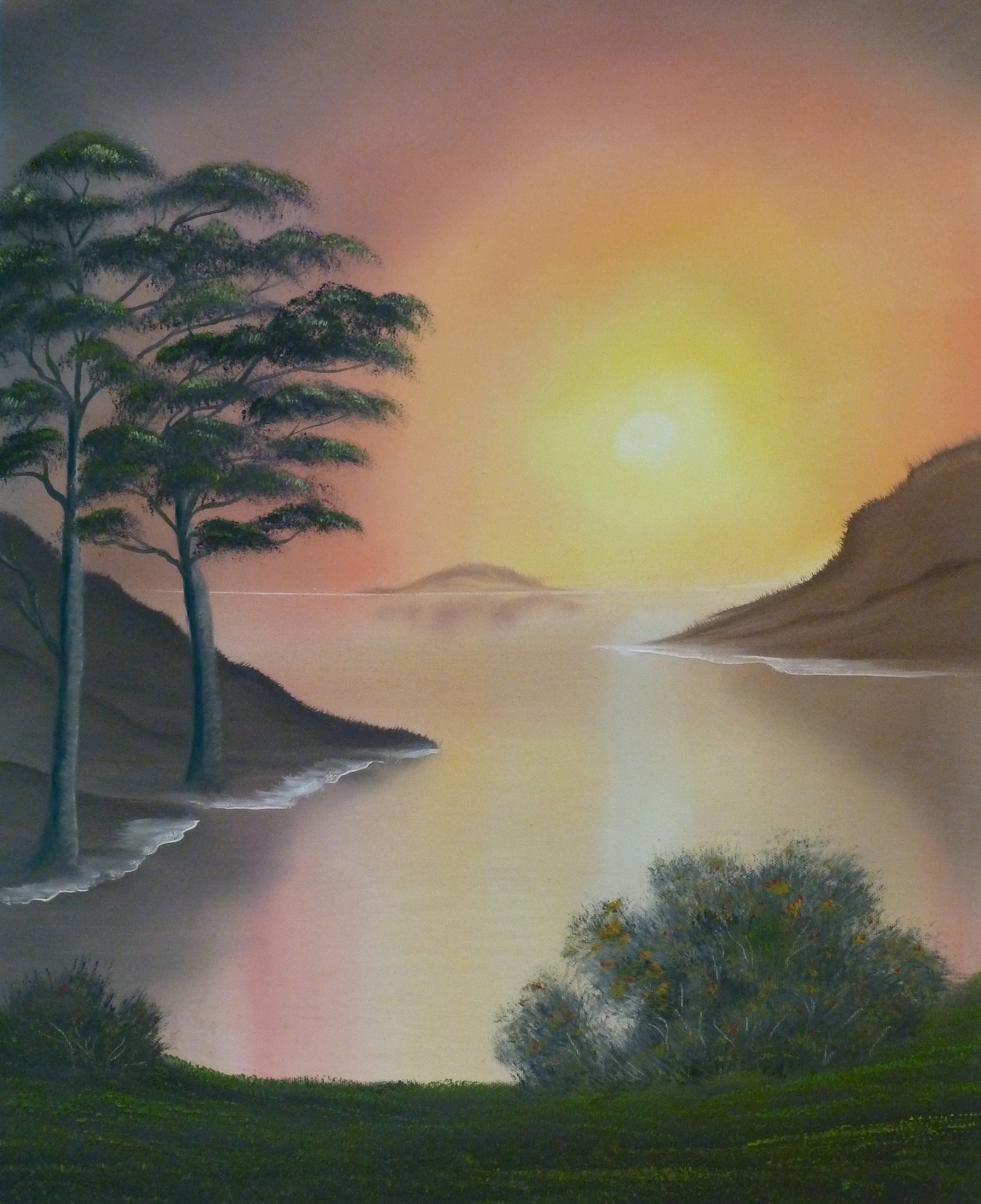 Stille Bucht mit Bäumen und Bergen im weichen Licht des Sonnenaufgangs.