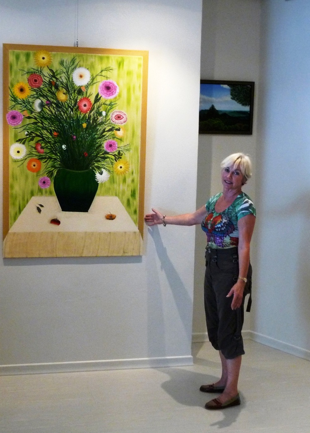 Bricia Lorenz in ihrer Ausstellung neben dem Gemälde eines Blumenstraußes